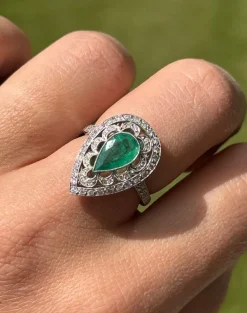 Bague de style Art Déco en platine avec une émeraude centrale et des diamants.