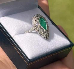 Bague de style Art Déco en platine avec une émeraude centrale et des diamants.