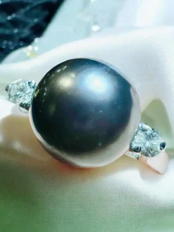 Bague en or blanc, perle de culture grise entourée de 2 diamants