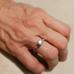 Bague solitaire en or blanc avec diamant central et diamants sur la tige